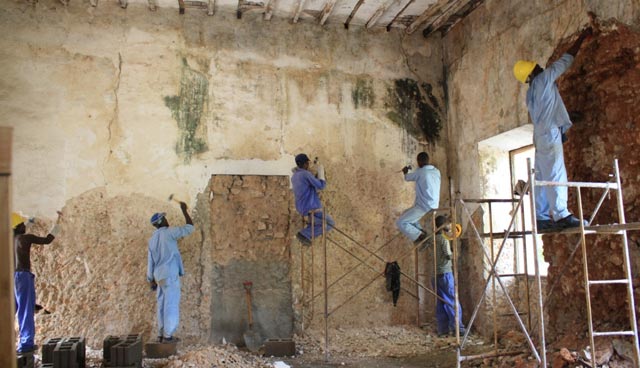 Workers remove old lime plaster from the walls of an 18th-century building on Mozambique Island.