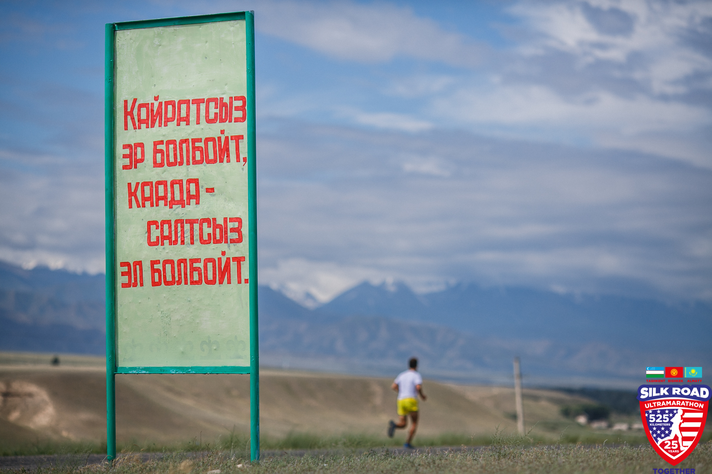 Dean running on road with sign in foreground 
