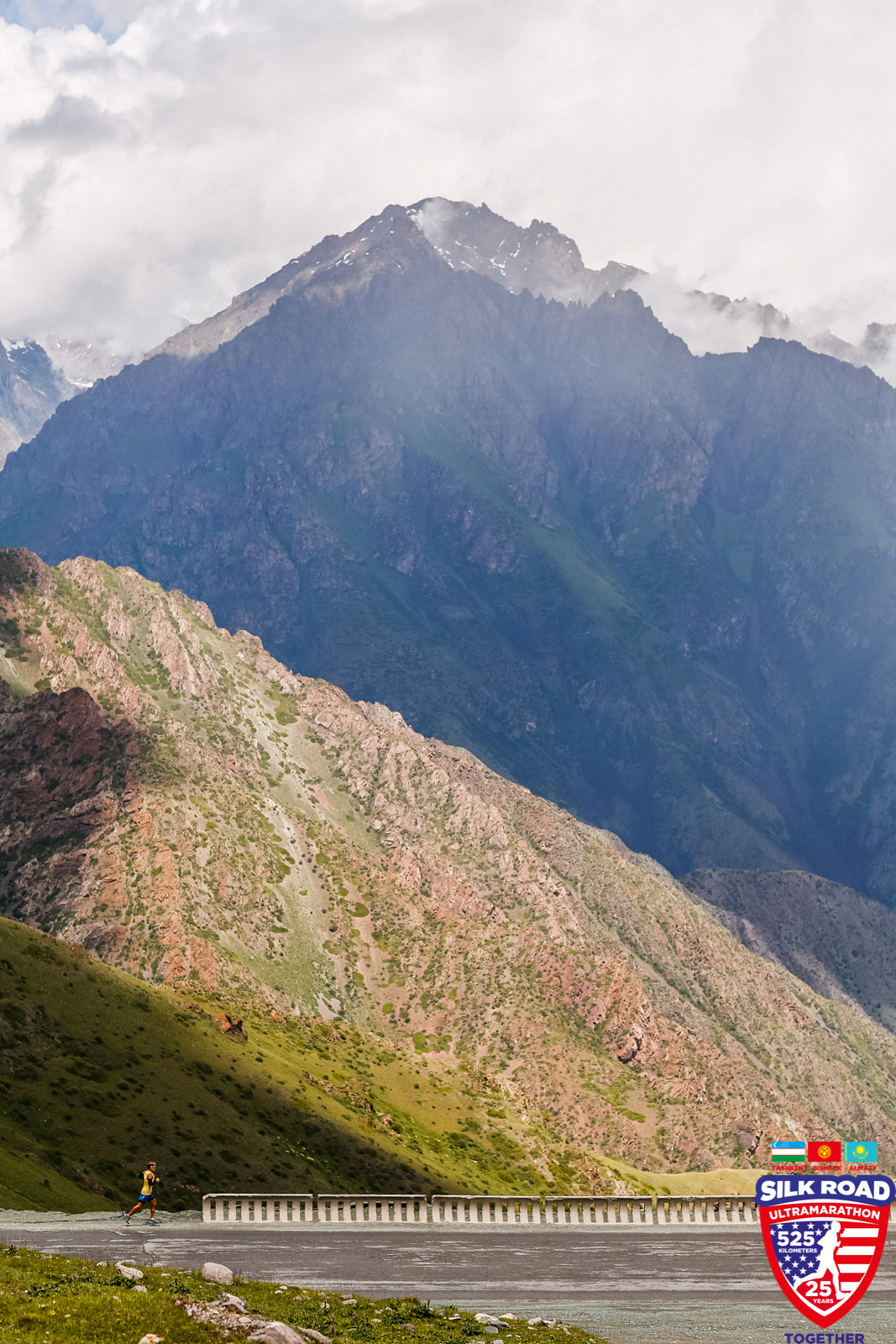 Dean is a tiny figure in a yellow shirt next to the towering mountains of the Kyrgyz Republic 