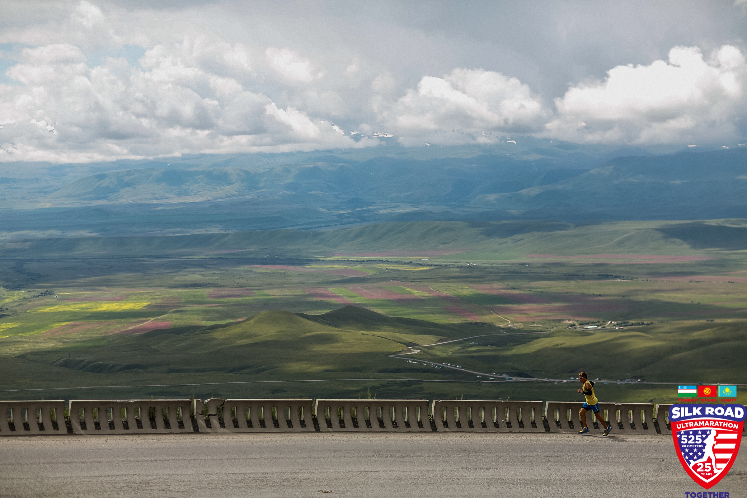 Dean runs next to an expansive view of fields, mountains, and clouds