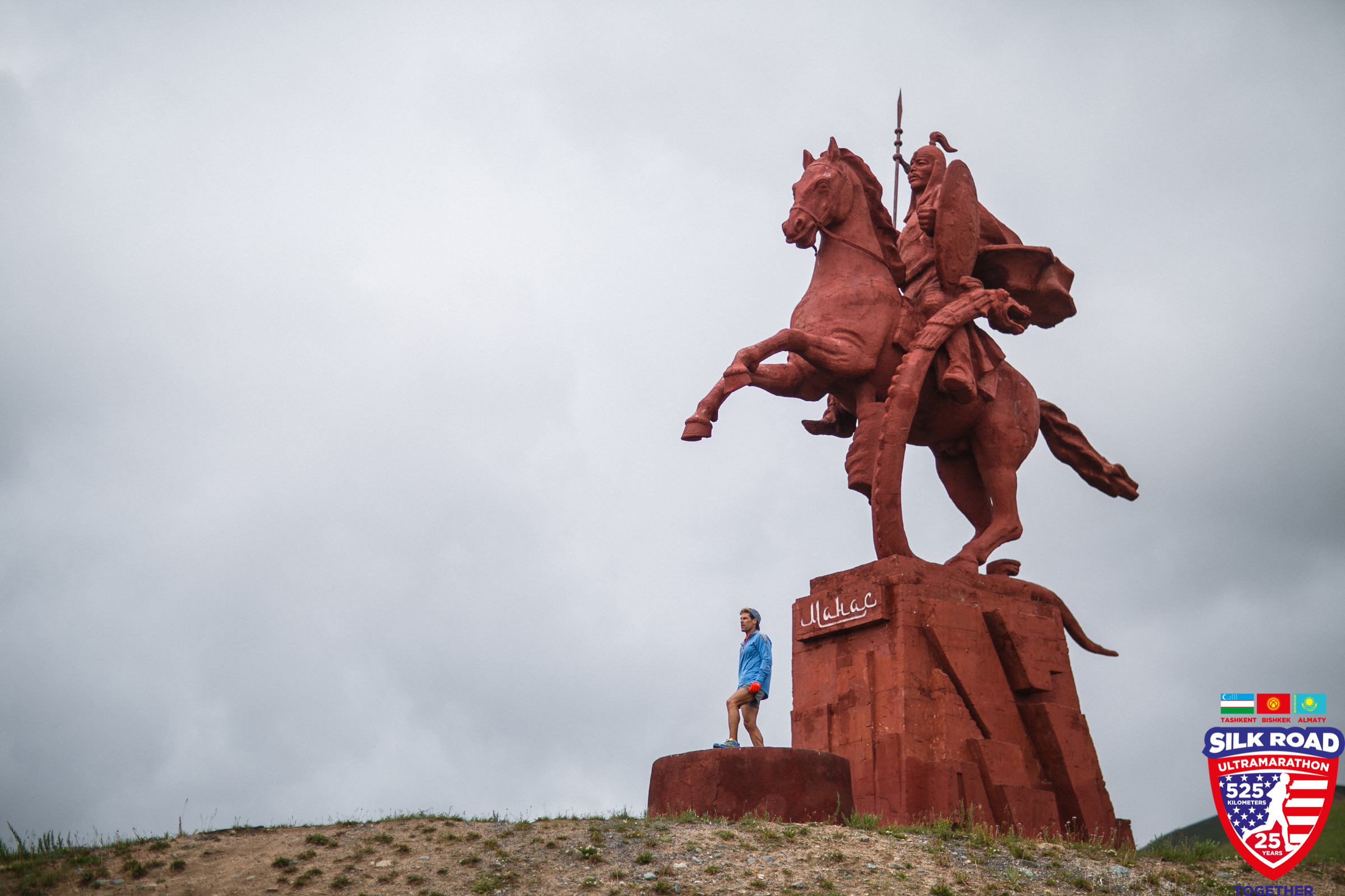 Dean posing in front of a giant terra cotta colored statue of a rearing horse and rider