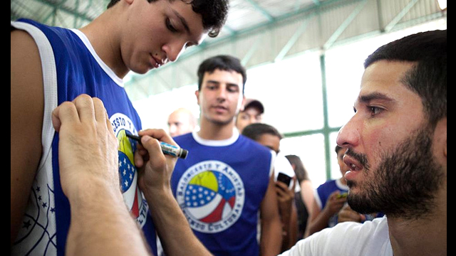 Teenage fans line up for Greivis Vasquez's autograph after a basketball session.