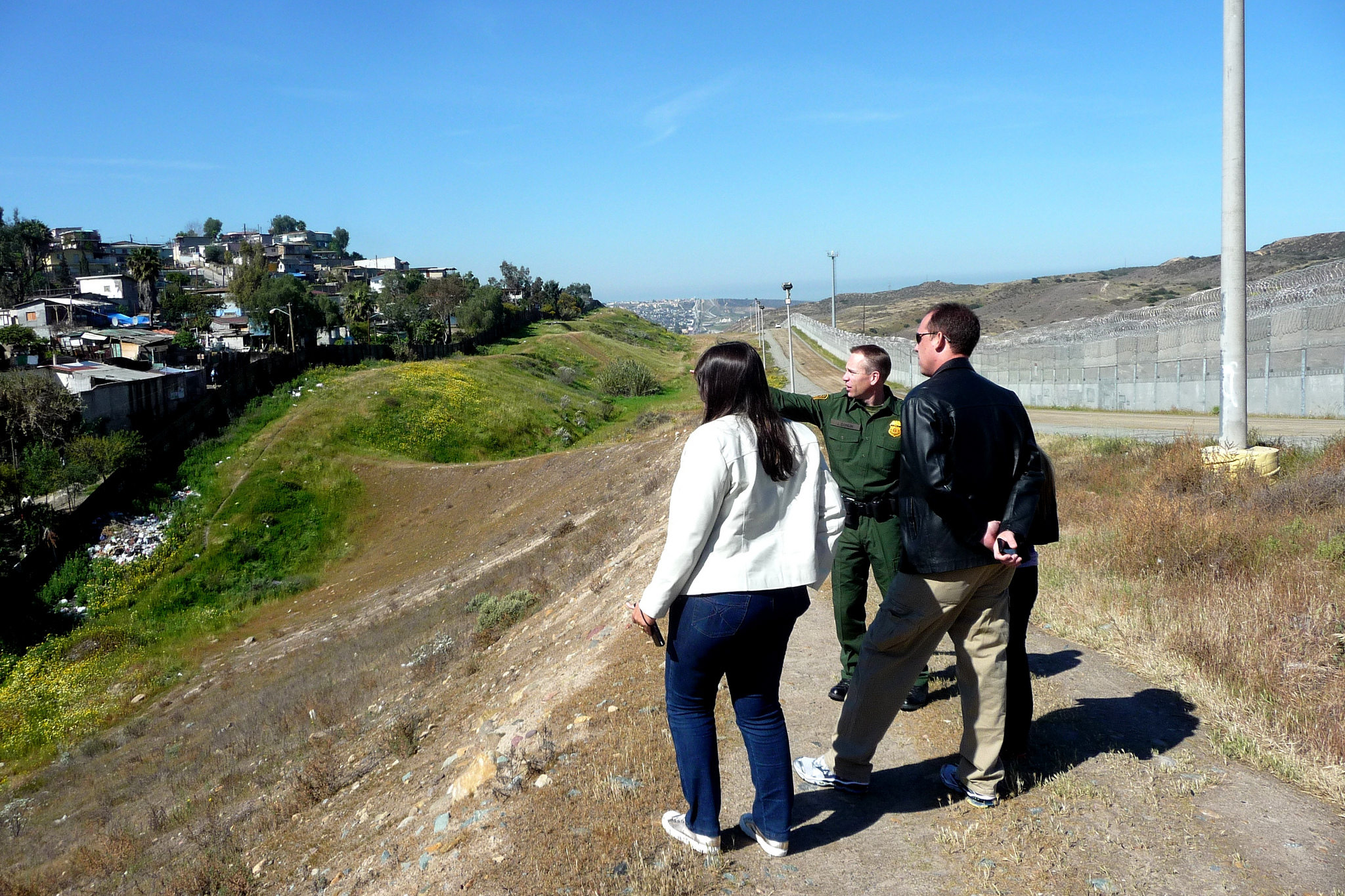 Two people standing on hill look at field a ranger is pointing towards