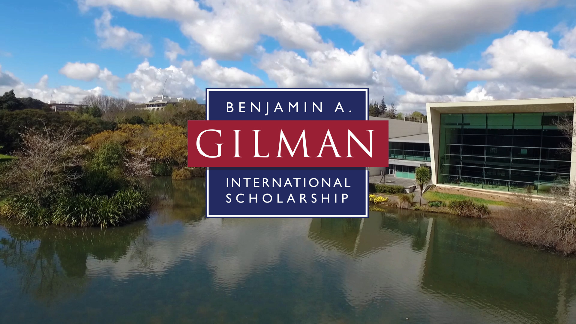 Wide shot of the front of a building with a lake of water around it and the title graphic on top