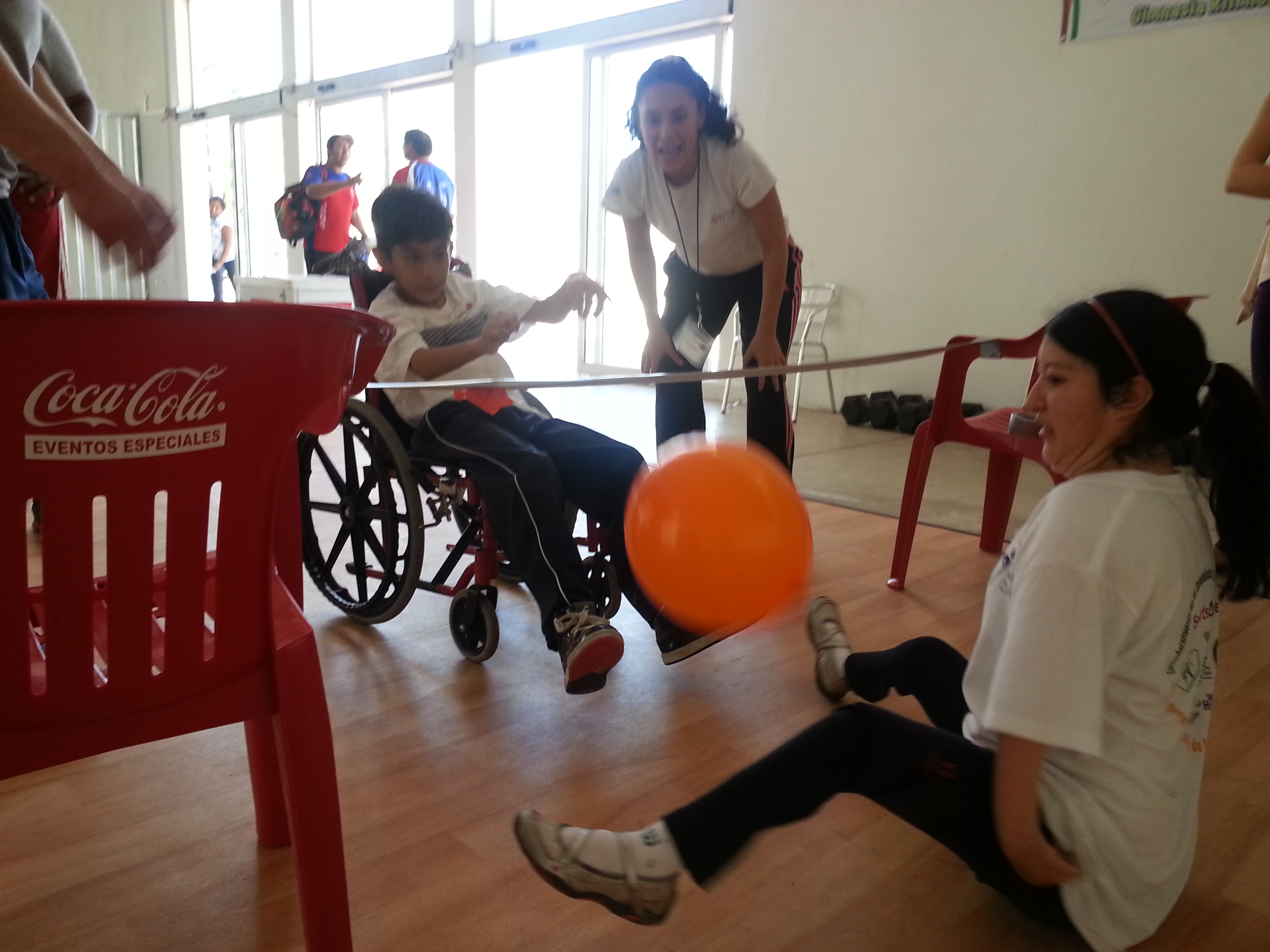 A girl with arthrogryposis practices her sitting volleyball with a teammate