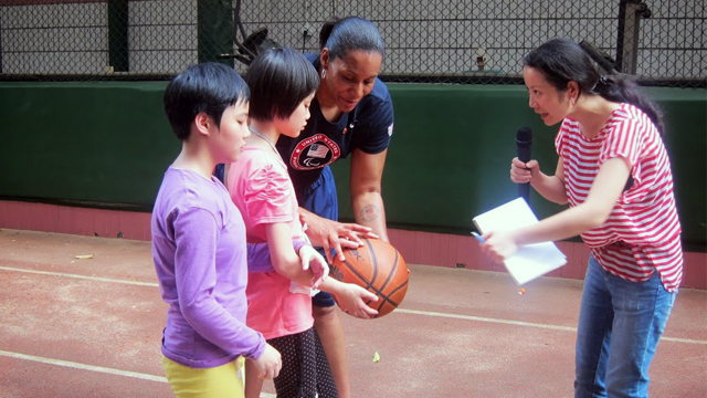 Dr. Woodson-Smith assists a blind student with a basketball at Peiying Vocational School. 