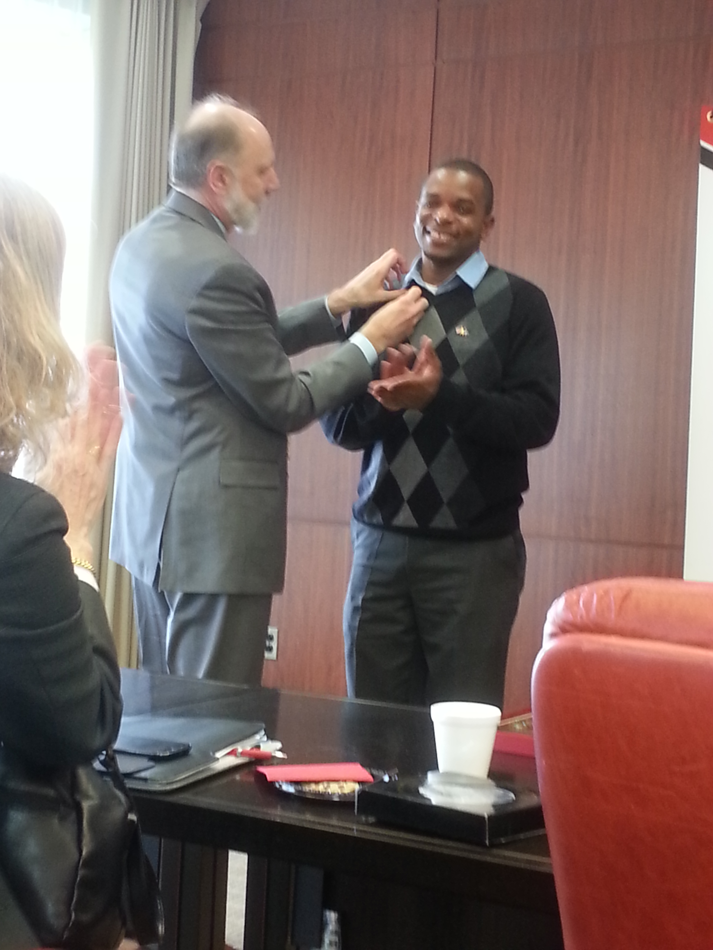 President Baker presenting delegate Bernard with his NIU sport pin