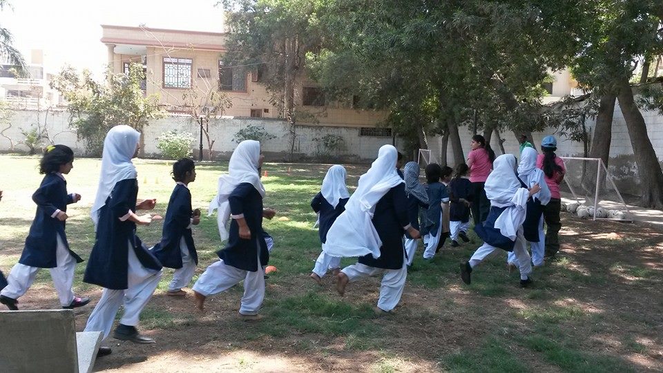 Fatima and her fellow coach lead the girls in a running warmup during a GO GIRL camp