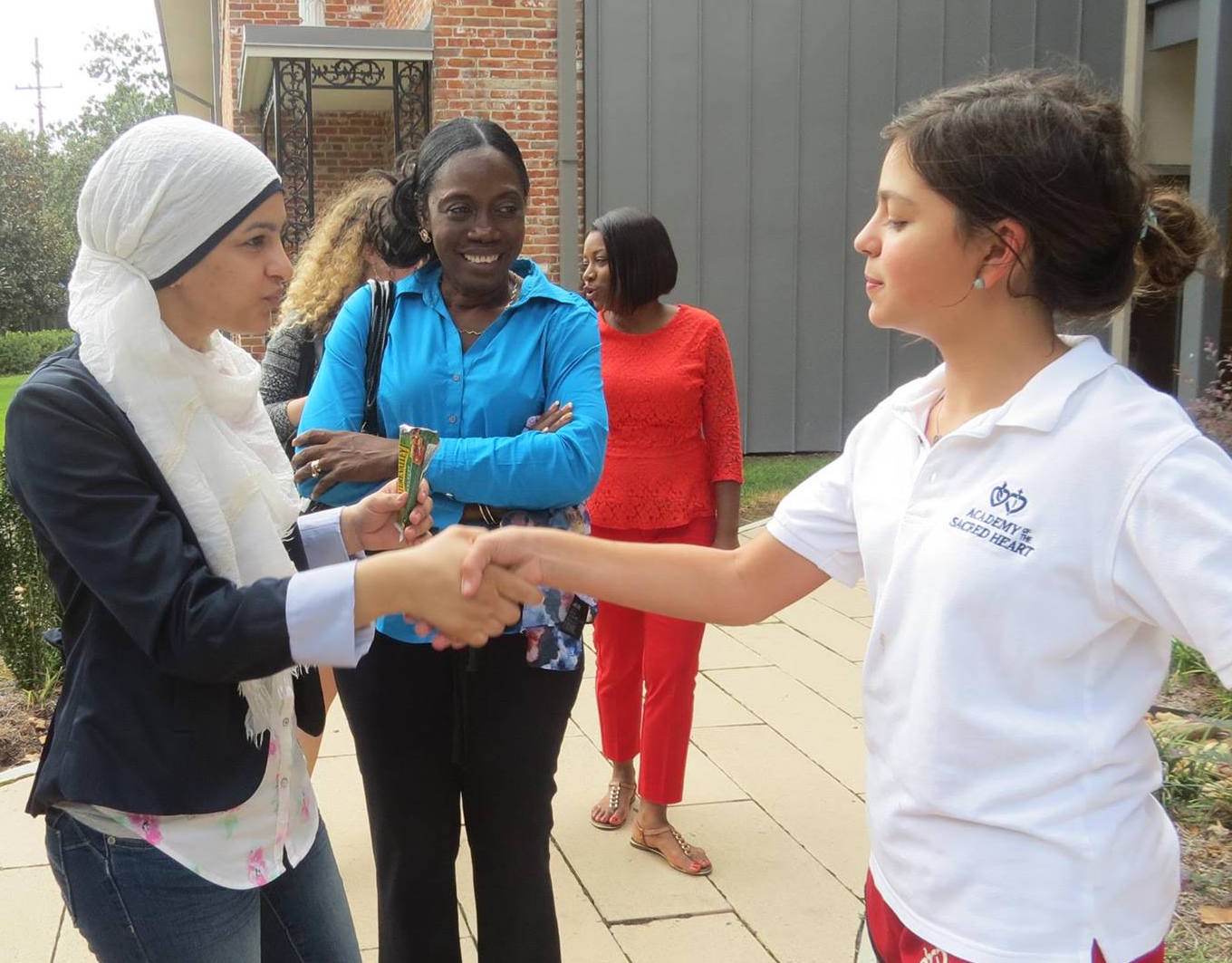Women participant shaking hands with girl student during volunteer activity