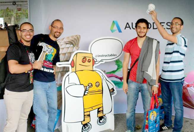 Men holding up with drawings and standing next to Robot poster