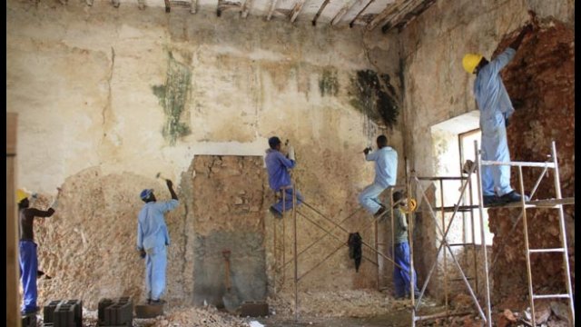 Workers remove old lime plaster from the walls of an 18th-century building on Mozambique Island.