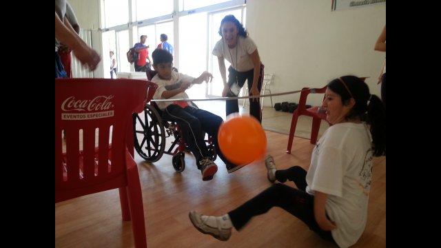 A girl with arthrogryposis practices her sitting volleyball with a teammate