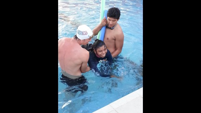 A young girl with cerebral palsy enjoys a swimming class