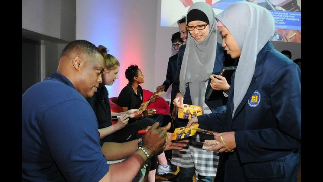 Rick Mahorn, Becky Bonner, and Edna Campbell sign autographs for the participants in Indonesia.