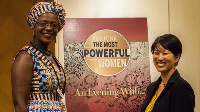 A woman in African dress and Asian woman standing in front of a sign reading "Fortune:The Most Powerful Women".