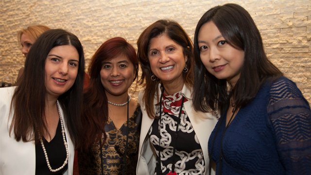 Four women in professional attire smiling at the camera