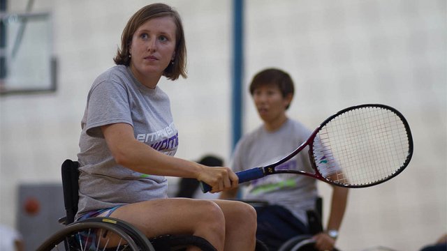 Woman in a wheelchair holding a tennis racquet