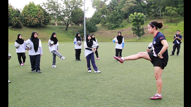 Sports Envoy, Danielle Slaton, gives the girls tips on kicking.
