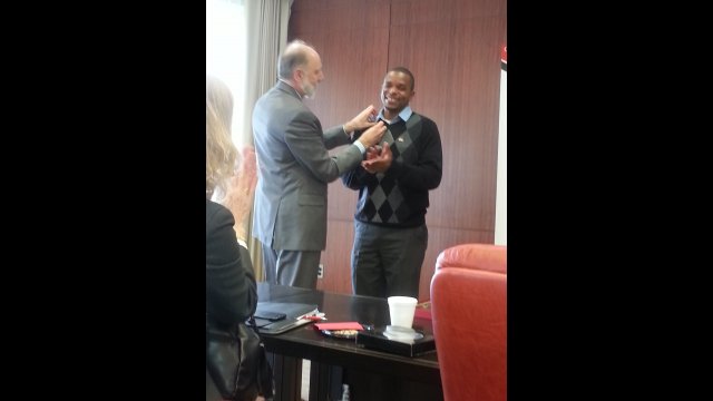 President Baker presenting delegate Bernard with his NIU sport pin