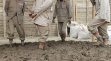 Workers are preparing mud bricks the traditional way for use in the ruined walls of Caral in Peru.