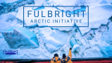 Two Arctic researchers looking down on to Arctic ice from the deck of their research boat.