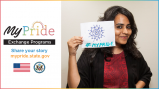 Smiling Indian woman holding up a hand-draw sign with a mandala and #MyPride written on it