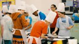 Group of children in a classroom wearing chef hats and aprons