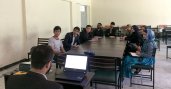 Group of young adults sit around a table in a classroom