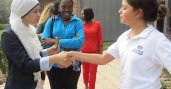 Women participant shaking hands with girl student during volunteer activity