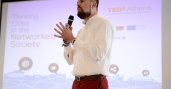 Man holding a mic on stage giving a presentation