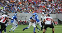 Football player running between opposing players with the football