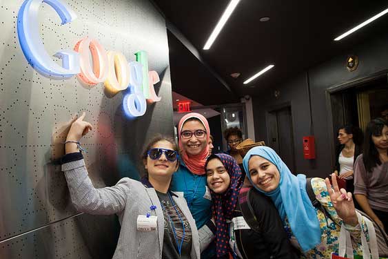 Girls posing in front of Google sign on the wall