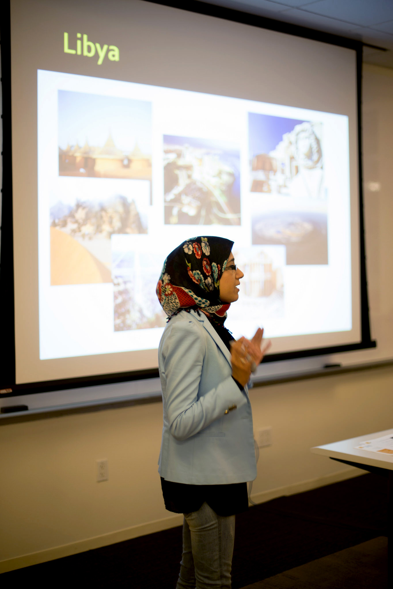 Woman standing in front of projection screen giving a presentation on Libya